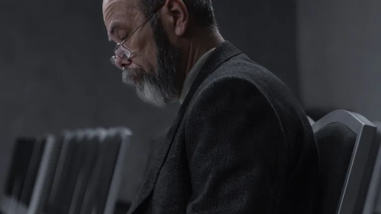 A man sitting in hall with chairs looking at notes.