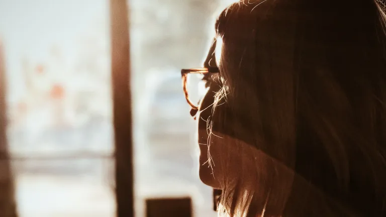 Those who deceive must first win us over. A woman looking out a window.