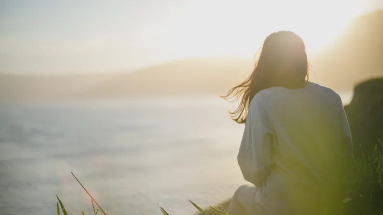 Love, as the word is used in the Bible, is primarily about action—how we treat others, motivated by a mindset that considers others better than ourselves, that wants the best for them, that puts their needs ahead of our own. A woman sitting watching the sunset.