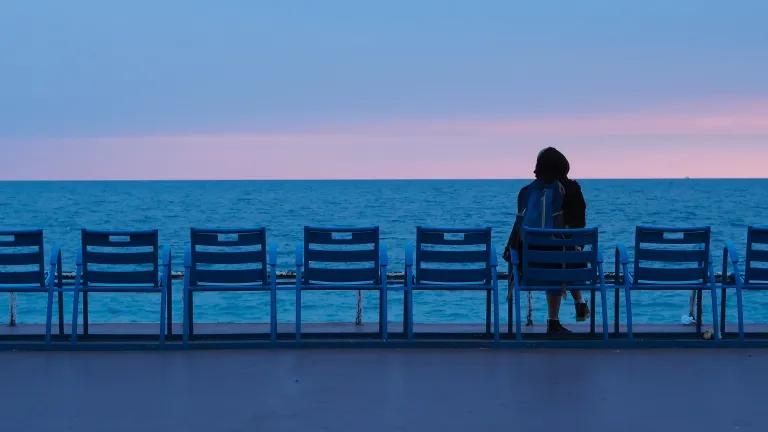 A person sitting watching the water of a sea.