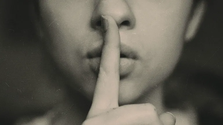 Picture of a person with finger over their lips.