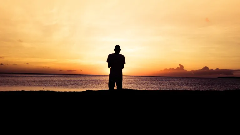When God begins working with us, we start to see that our natural way of life—which appears well and good to us—leads spiritually nowhere. A person standing by a body of water at sunset.