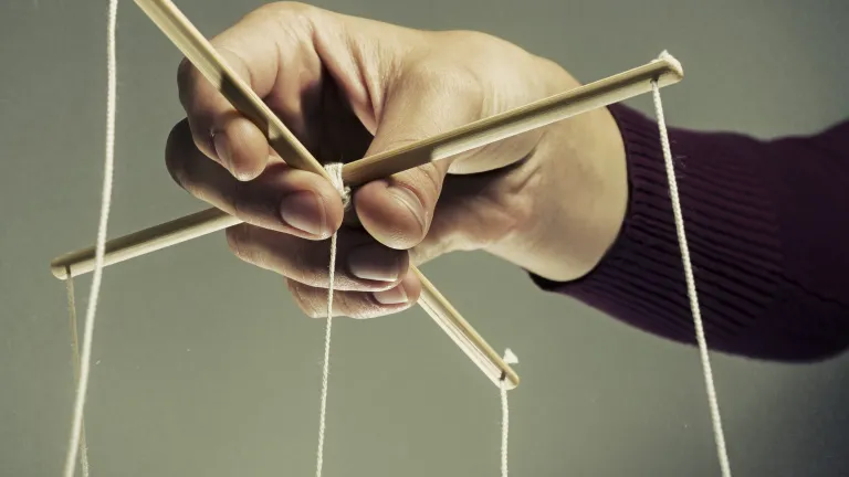 A person holding a puppet strings.