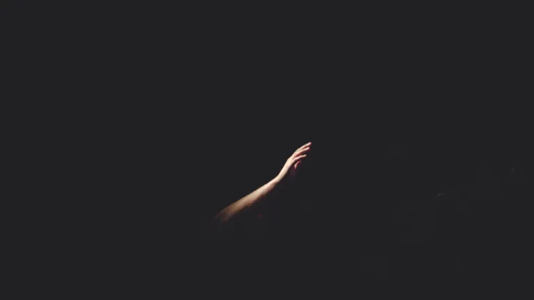 Hand reaching out of the darkness upward