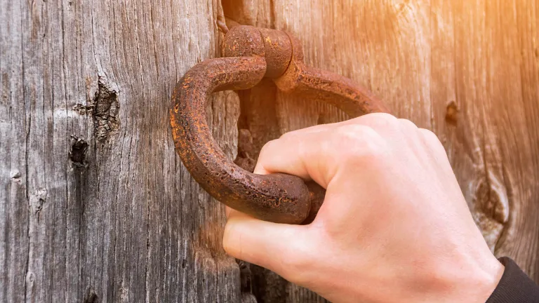 The question is not whether He will knock, as He certainly will. The real question is whether we will open the door and respond. A person holding onto a door knocker.