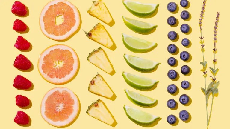 Rows of fruit aligned geometrically including pineapples, blueberries, raspberries and limes