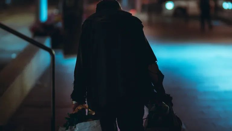 Homeless man walking down street at night under street lights