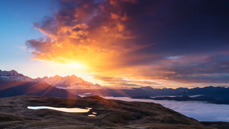 Sunrays over a mountain and a lake.