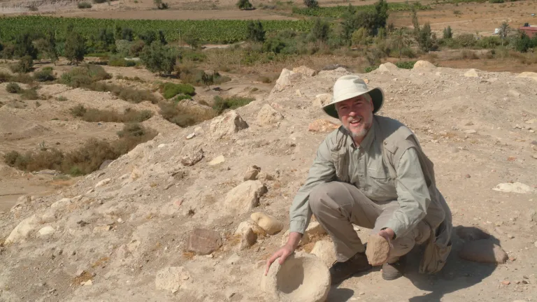 The author examines a stone grinder and bowl at Tall el-Hammam before excavations began. The author examines a stone grinder and bowl at Tall el-Hammam before excavations began.