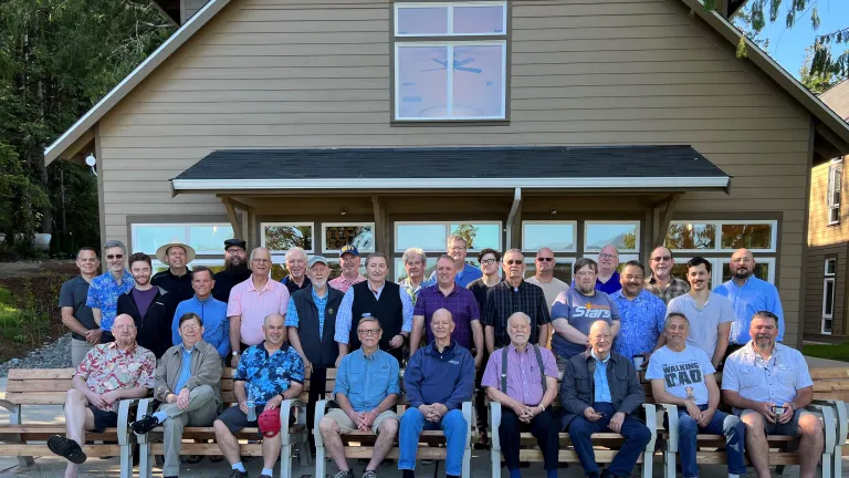 A group of 33 men enjoyed a great weekend together, with the theme "Strengthen Your Brethren." A group of men sitting and standing in front of a building.
