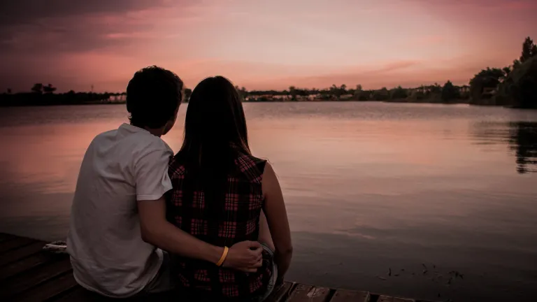 How Far Is Too Far? Girl and guy sitting on a dock looking at the sunset