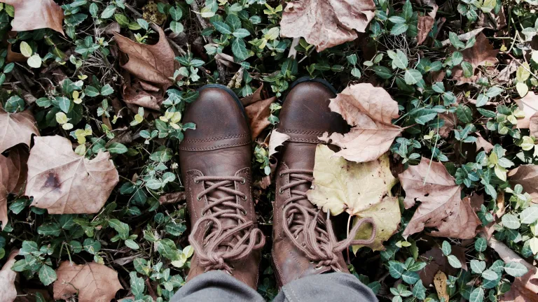 a pair of feet with boots on the leaf-strewn grass