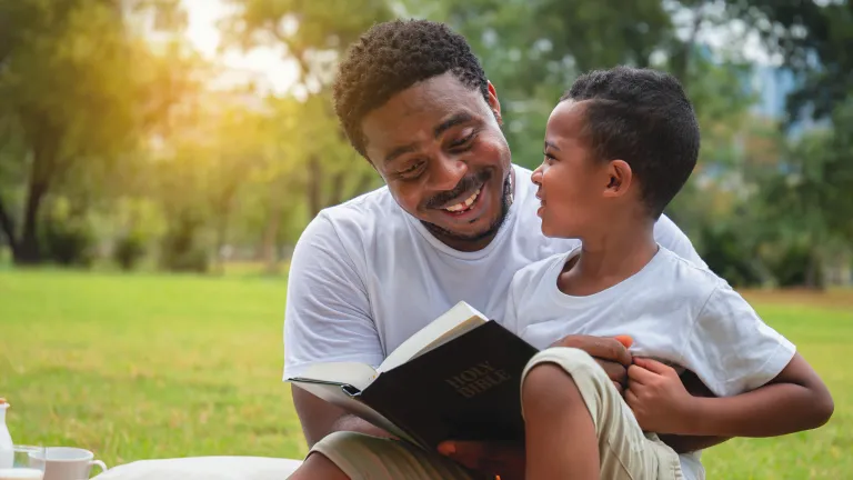 We all have stories to share with our children, stories of God’s faithfulness in our lives. Share those stories. A dad talking to his son while holding a Bible.