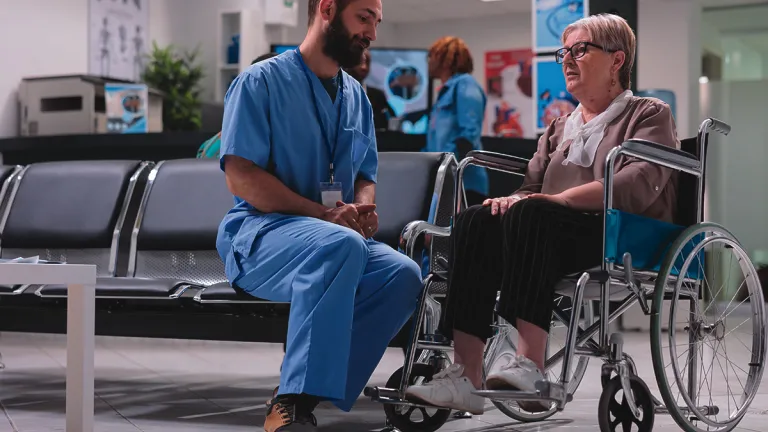 A doctor talking with a patient in a wheelchair.