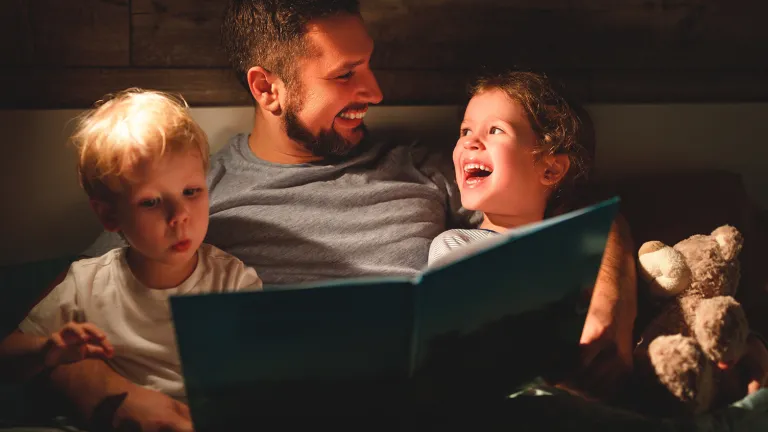 As parents, we want our homes to be a safe haven in which our children can sharpen their spiritual muscles. A father reading a book to his kids.