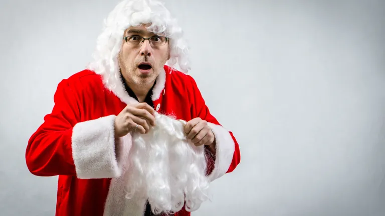 A man putting on a Santa Claus costume.