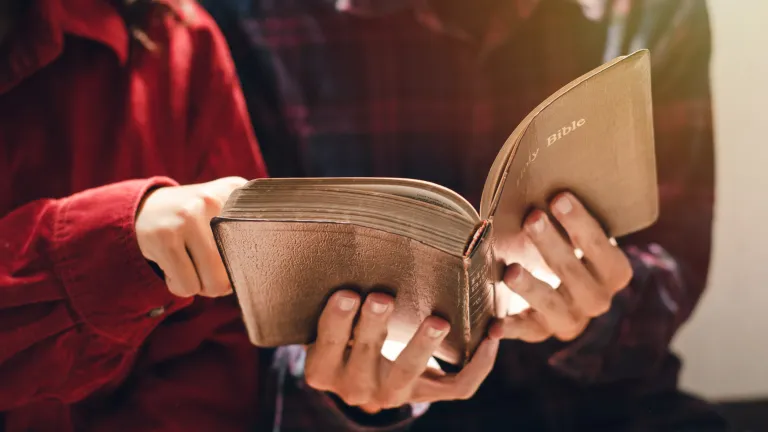 Two people looking at an open Bible.