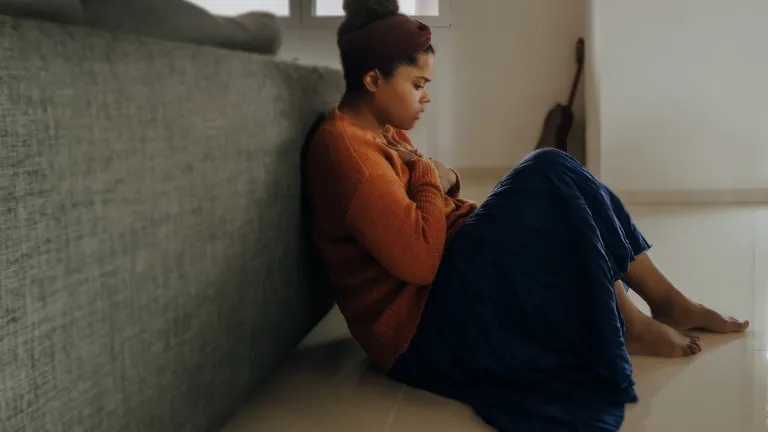 None of us can counter Satan on our human strengths alone. We need God’s help. We need to draw near to Him, as our greatest defense against Satan is a right relationship with God. A woman sitting on the floor in thought.
