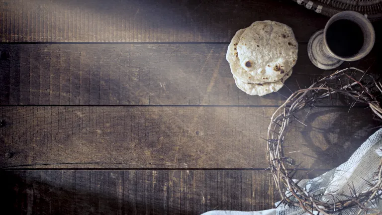 Unleavened bread, a crown of thorns and wine on a rich wood table