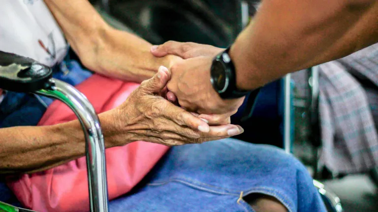 Where we can engage and make a difference, we should. But it’s far more important we come to see that we can start changing ourselves and begin a life of preparation for the world to come. A man holding an older woman's hand sitting in a wheelchair.