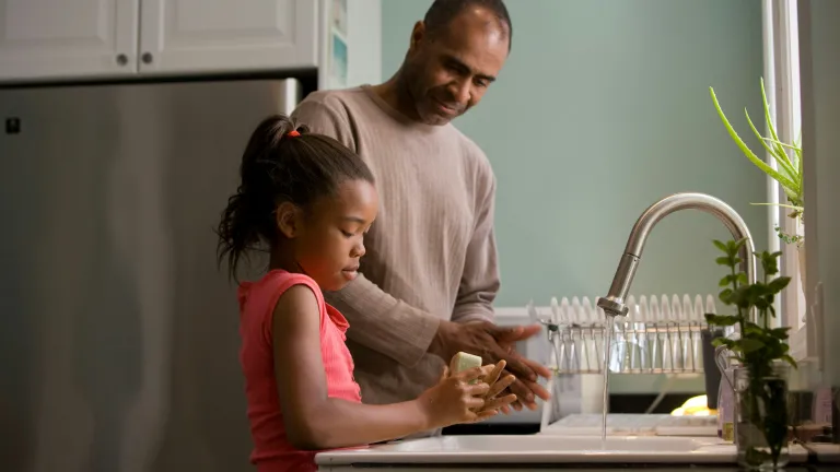a father and daughter washing hands together in the kitchen