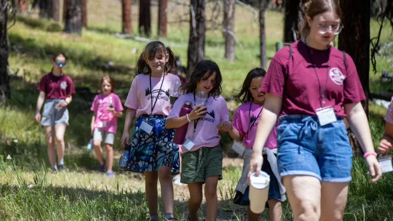 Camp Ochoco a line of girls walking through the grass and wearing matching pink shirts