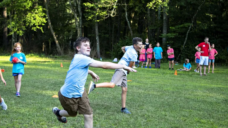 Camp Seven Mountains a group of children running and playing a game in a field