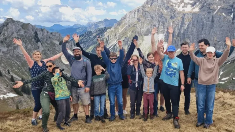 a group of hikers standing on mountainous terrain with mountains in the background