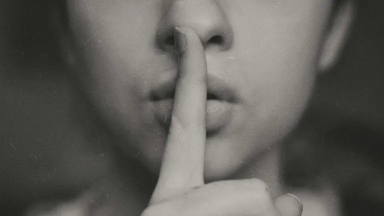 a woman with a finger to her lips in a gesture for silence