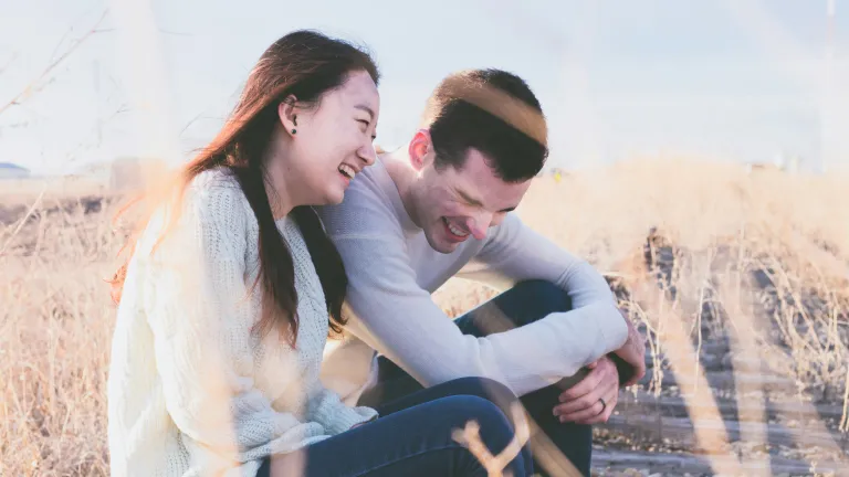 a man and a woman seated next to one another and laughing