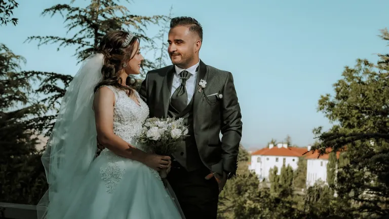 a bride and a groom looking at each other while standing outside