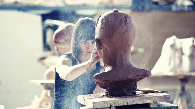 A woman sculpting a clay head.