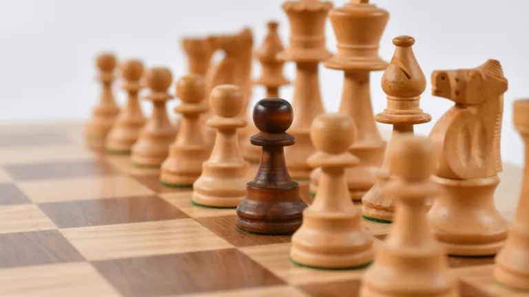 one different-colored pawn amongst a row on a chessboard