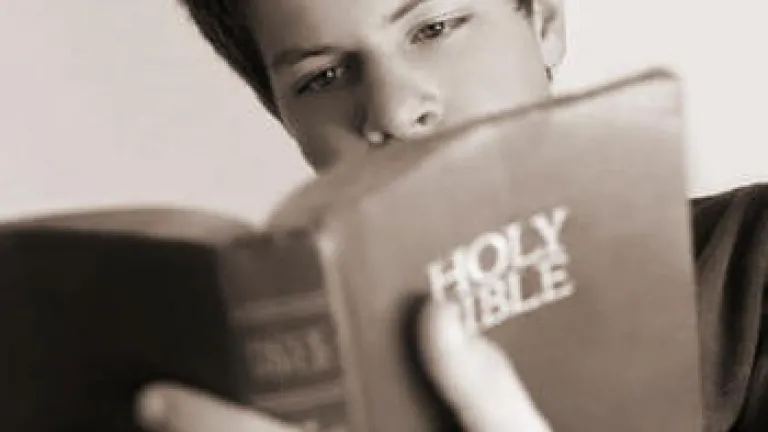 A teen boy looking at a Bible.