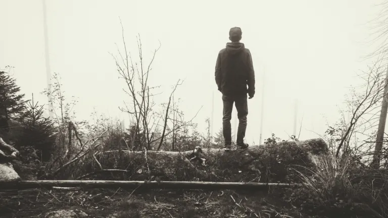 Climbing out of depression can be likened to trying to climb out of a slippery pit. We can set off with good intentions and then slide back in. It's a long journey, but we must keep at it with God's help. A young man walking in a foggy forest.