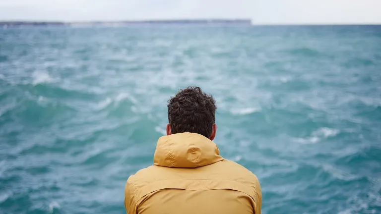 God may not intervene immediately in your life, but He will give you strength and will calm you while you go through your trials. A man watching the waves on a lake.