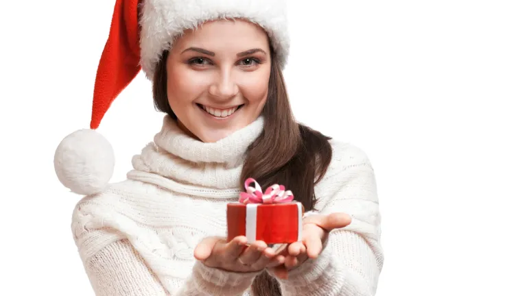 The problem with the modern Christmas celebration is that its origins have little to do with the real Jesus Christ. This isn’t hidden knowledge. A woman wear a Christmas stocking cap holding a gift.