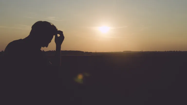 A man sitting with the sun in the background.
