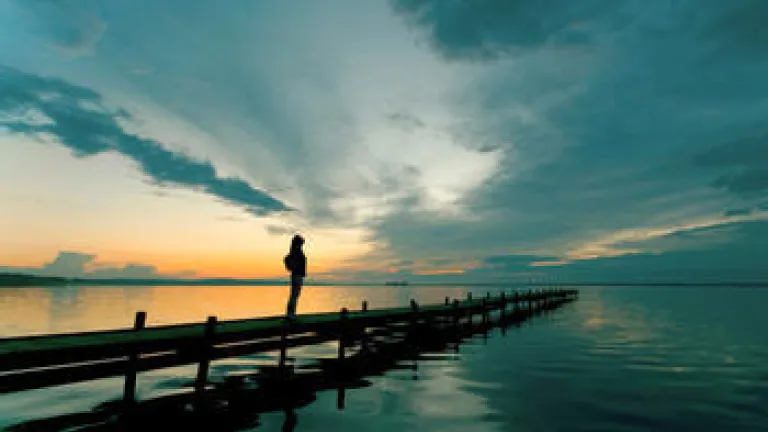 A woman on a dock looking up to the sky.