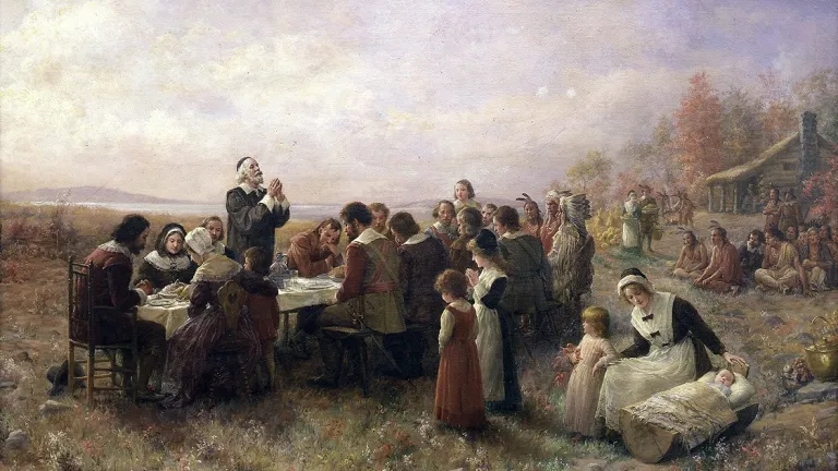 Painting of pilgims giving thanks during a meal.