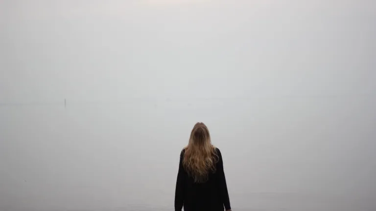 A woman standing by herself looking up.