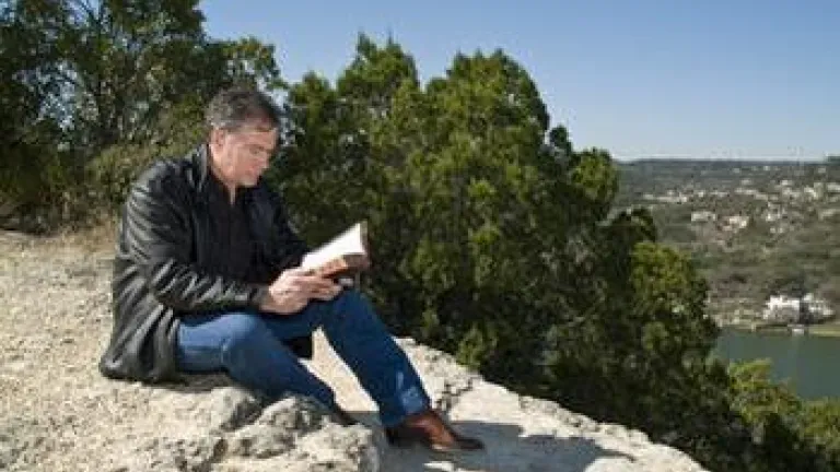 A man reading a Bible sitting outside.