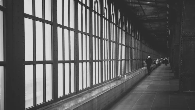 A long hall lined by windows with people walking in the distance.