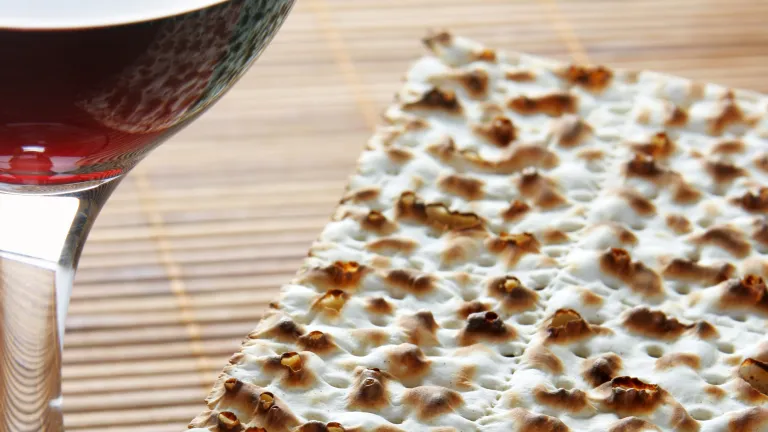 When we partake of the bread and wine, are we merely following a tradition? Does this ceremony have meaning for us in our era? A glass of wine beside flat unleavened bread.