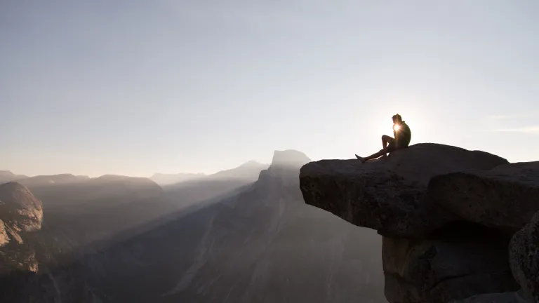 Any and all human efforts to create a perfect society fail because of one critical element—human nature. God has a solution for this problem. A person sitting on a cliff with sunset behind.