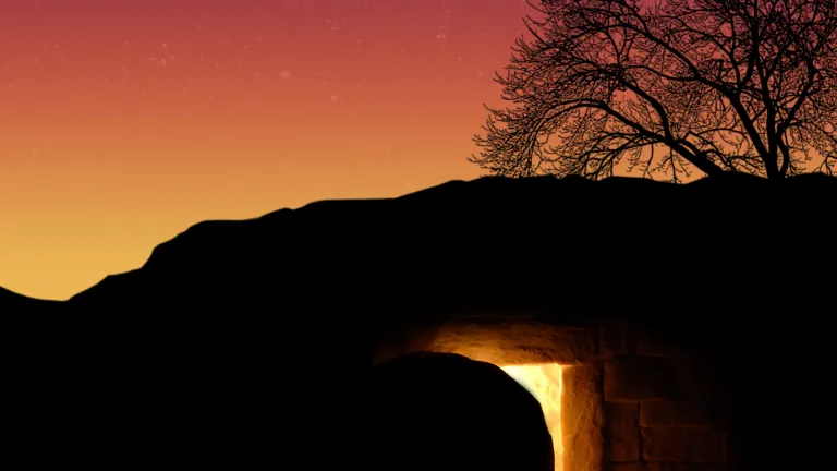 A tomb cut out of rock with a round stone next to the entrance.