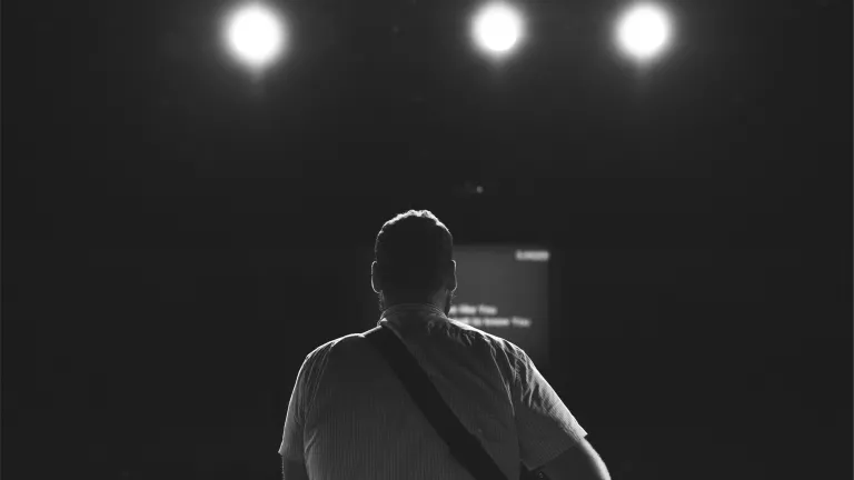 The back of a man looking at stage lights.