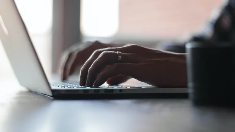 a pair of hands typing at a laptop computer