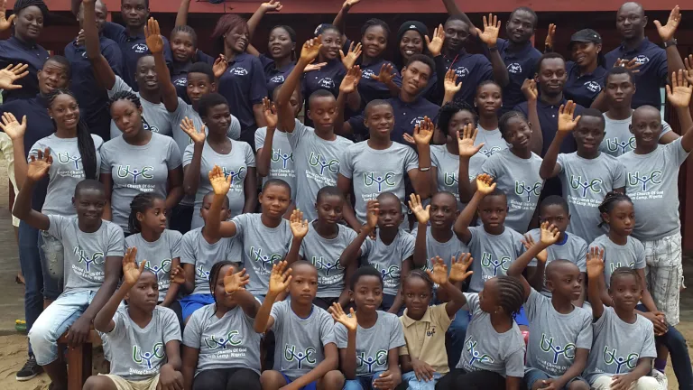 Campers and staff pose and wave at the camera.