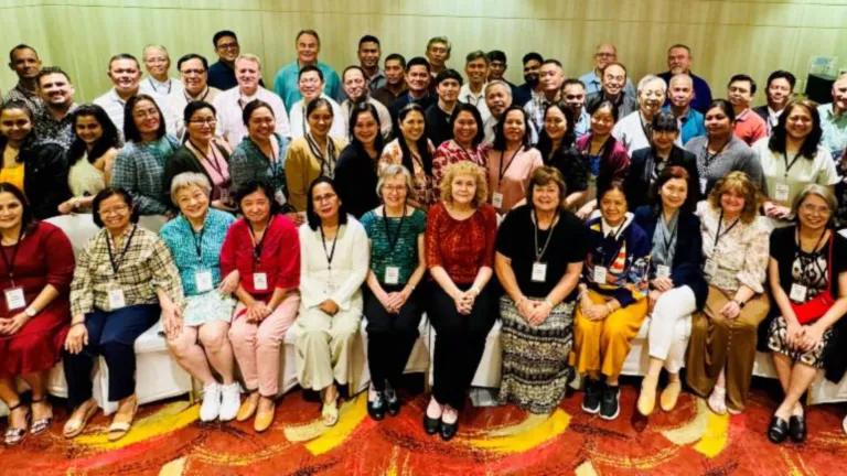 a large group of people seated and standing indoors